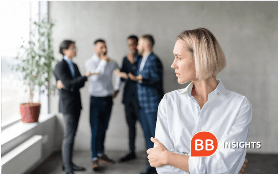 Woman looks over her shoulder at a conversation between men she's excluded from