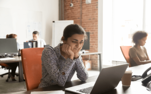 Indian female student looks at her computer while trying to decide between a PGDM and PGPM program © IStock